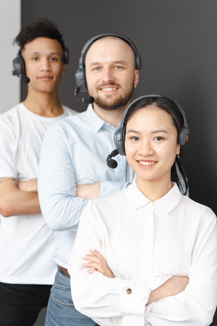A diverse team of customer service representatives wearing headsets and smiling.